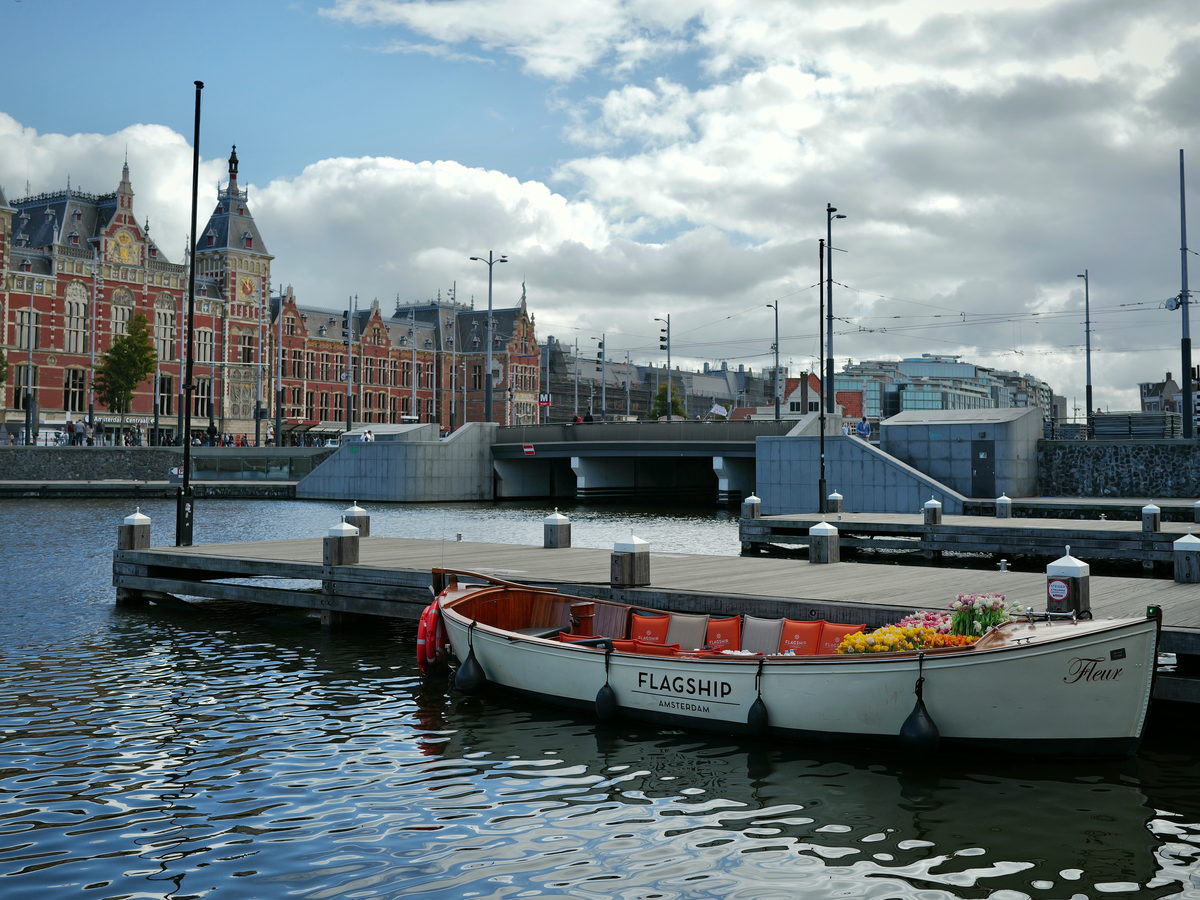 Open saloon boat with cushions at a jetty in front of Amsterdam Centraal